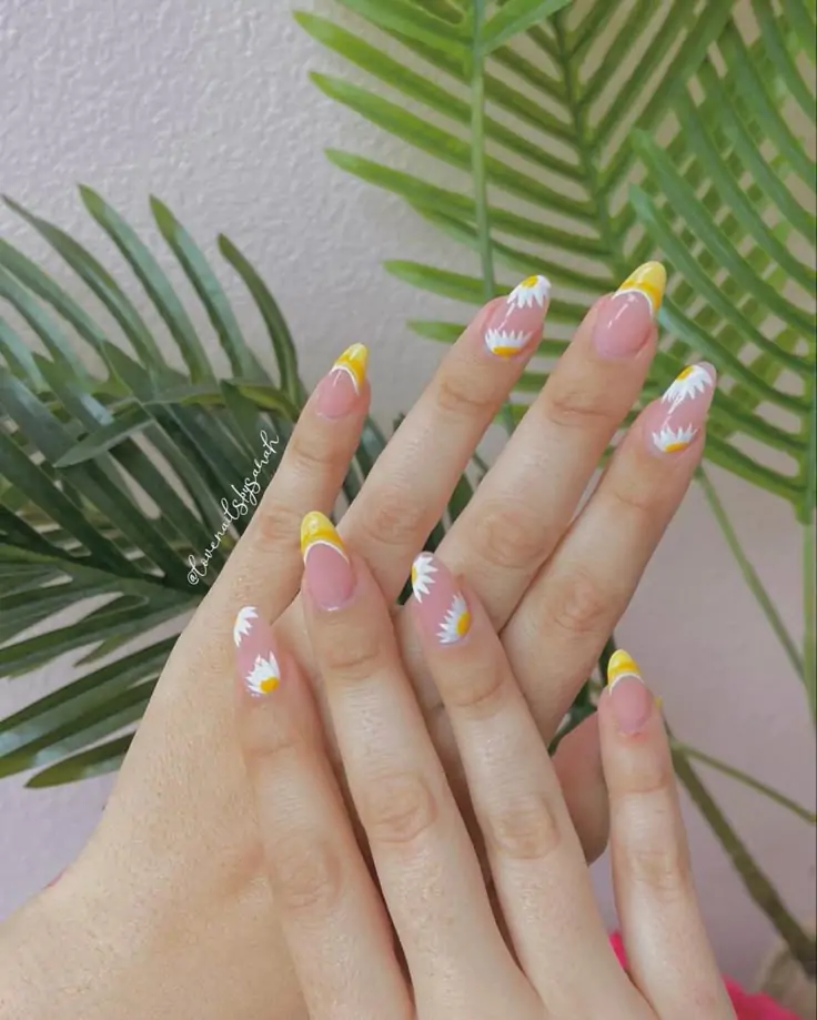 This nail design features a nude base for a chic beginning. French tips in a poppy yellow give a sunny ambiance. Hand-painted white daisies with yellow centers give a playful vibe, and the nails come alive. The almond shape enhances femininity, elongating the fingers. With a high-gloss top coat, this manicure has a sleek finish with enduring shine.