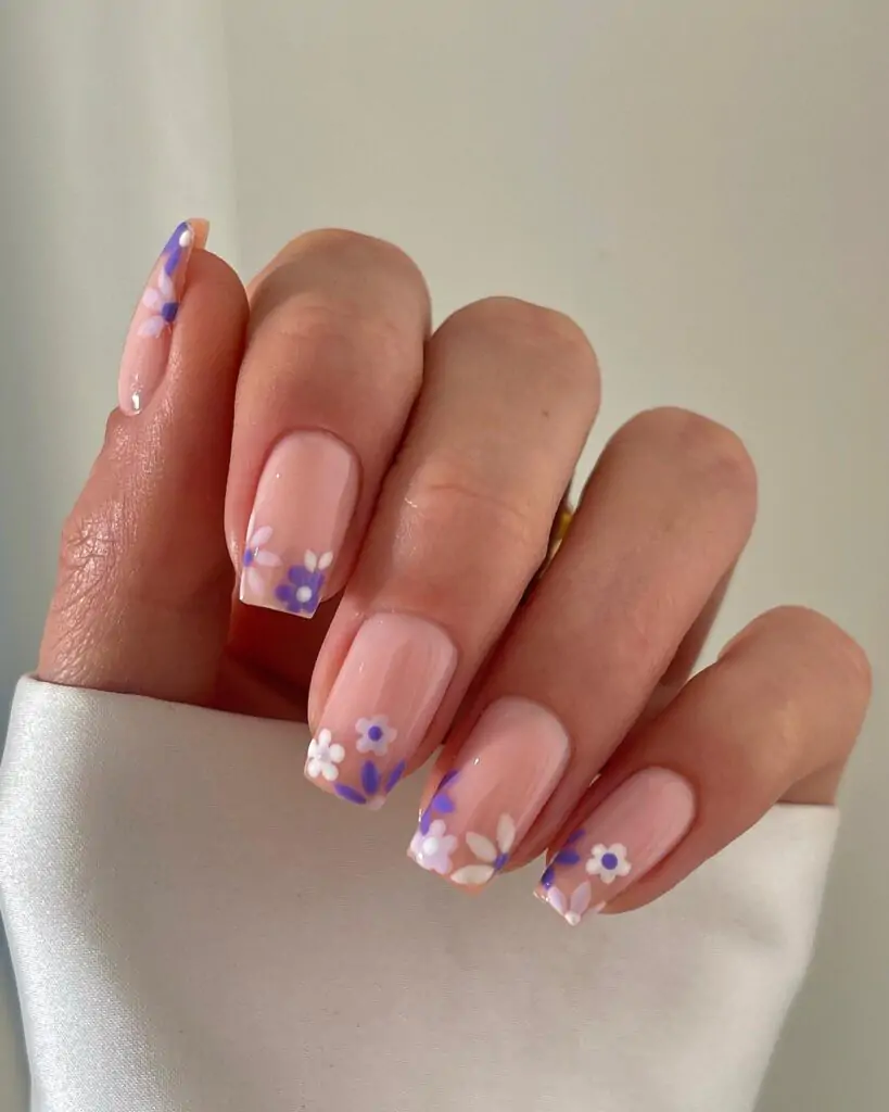 Spring tips are a temporary nail design with a pale pink color base and flower patterns. The flowers are typically purple and white, bordered by green leaves, for a spring-blooming, fresh look.