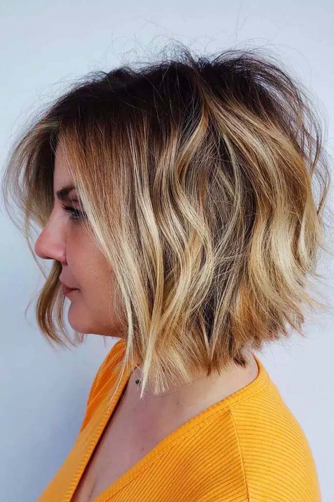 Inverted bob haircut with longer hair in the front and stacked layers in the back.