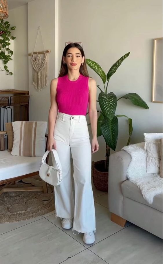 Fashion-forward individual in pink sleeveless top and white flared trousers with matching sneakers and shoulder bag