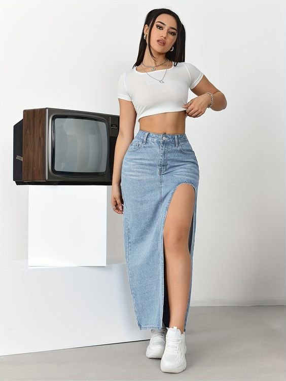 Fashion-forward casual outfit featuring cropped white tee, high-waisted denim skirt with thigh-high slit, and white sneakers.