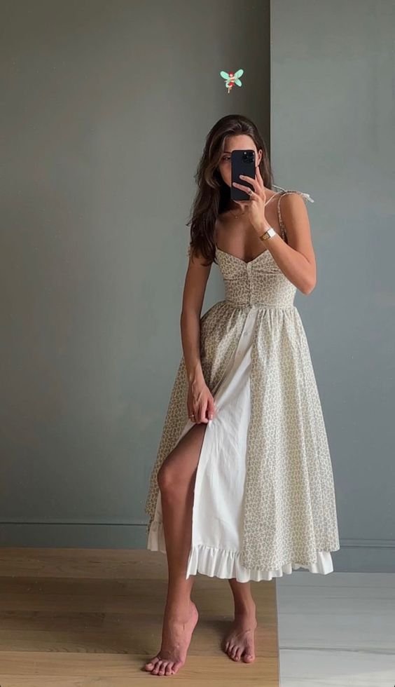 A woman showcasing a stylish sleeveless summer dress with polka dot design and an asymmetrical hemline.