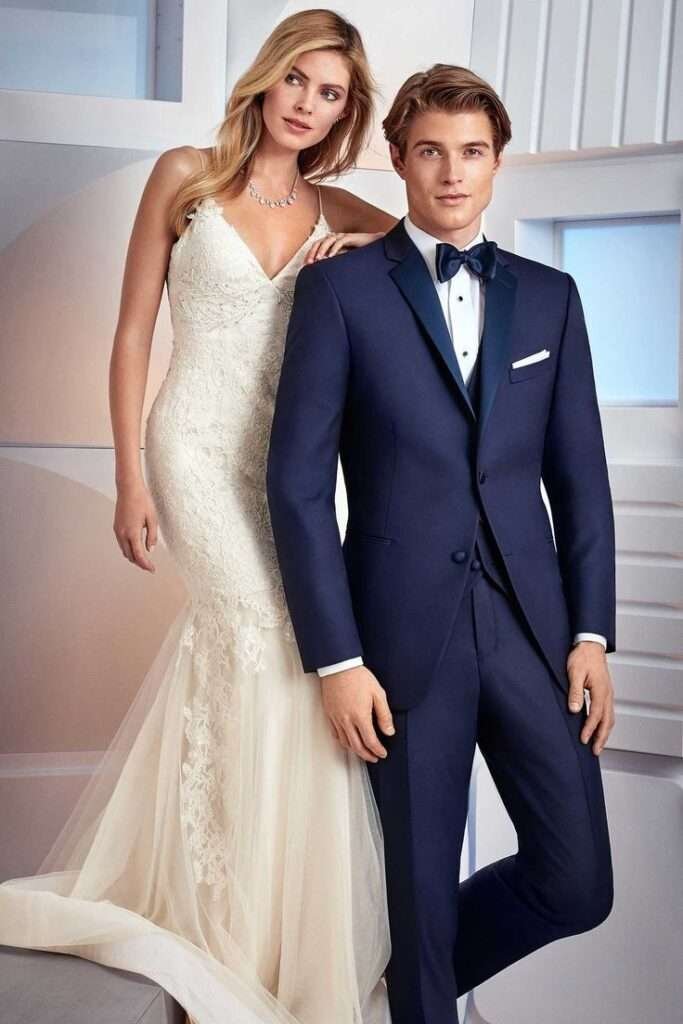 Elegant couple at a wedding, featuring a groom in a navy tuxedo and a bride in a lace wedding gown."