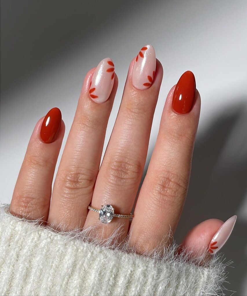 Close-up of fall-inspired nail art with burnt orange base, white accents, and leaf patterns