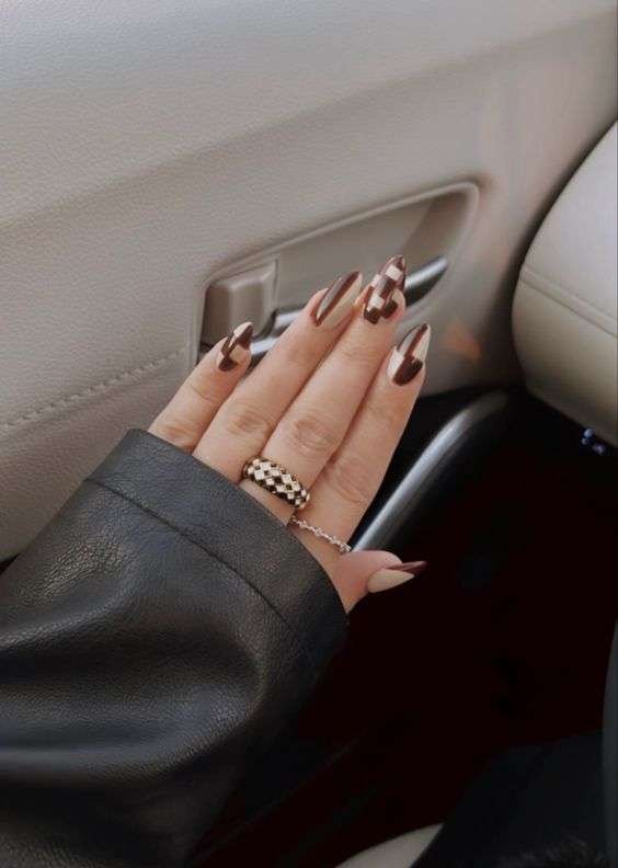 Fall nail design with glossy and matte finishes in earthy tones, sharp stiletto shape, and cream leather car interior.