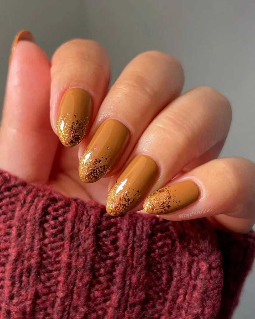 Mustard-colored nails with gold glitter tips, a chic fall manicure idea.