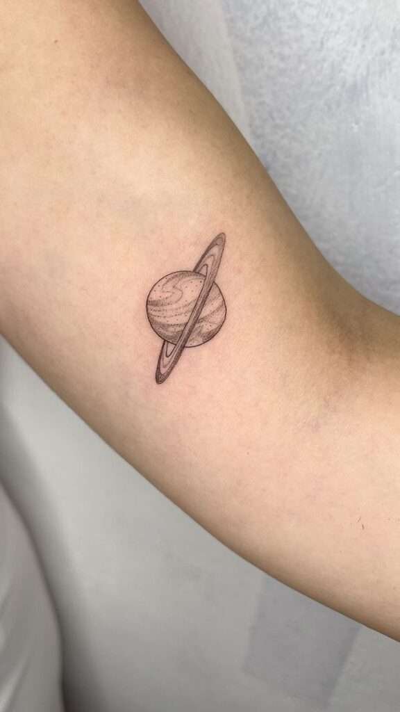 For those who love space and the cosmos, a tiny planet tattoo is a fun and quirky minimalist option. It can represent curiosity, exploration, and a connection to the universe. minimalist planet tattoo, small space tattoo ideas, simple planet tattoos