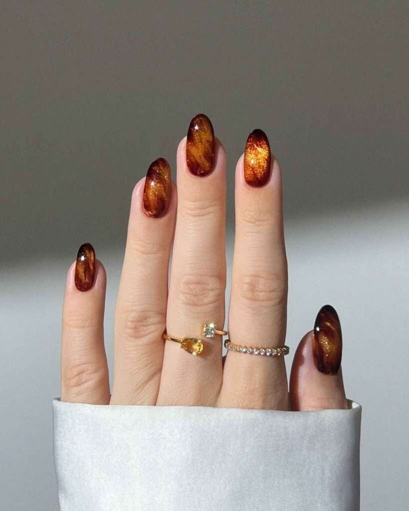 Fall-inspired nails with amber gradient and glitter, perfect for autumn