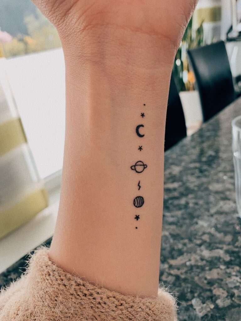 For those who love space and the cosmos, a tiny planet tattoo is a fun and quirky minimalist option. It can represent curiosity, exploration, and a connection to the universe. minimalist planet tattoo, small space tattoo ideas, simple planet tattoos