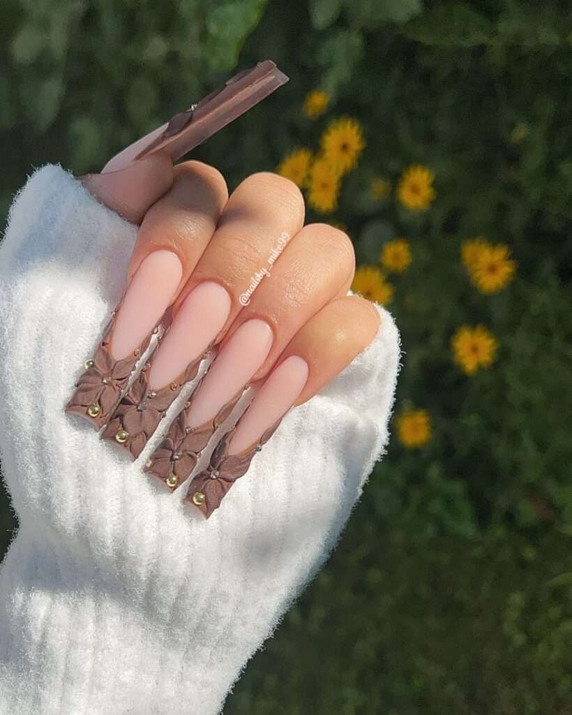 Fall nail design with peach base, gold studs, and brown lacing details on coffin-shaped nails.