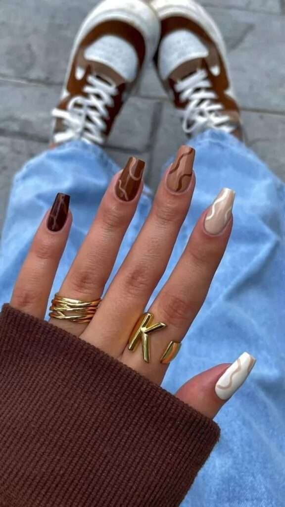 Retro-inspired brown and beige fall nails with wavy patterns.