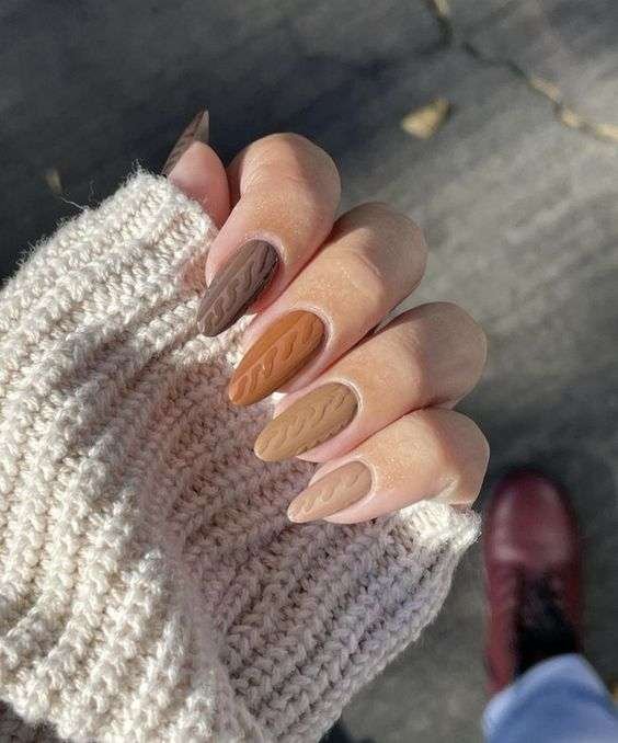 Hand with fall-inspired nail art in earthy tones of brown, tan, and beige, perfect for autumn.