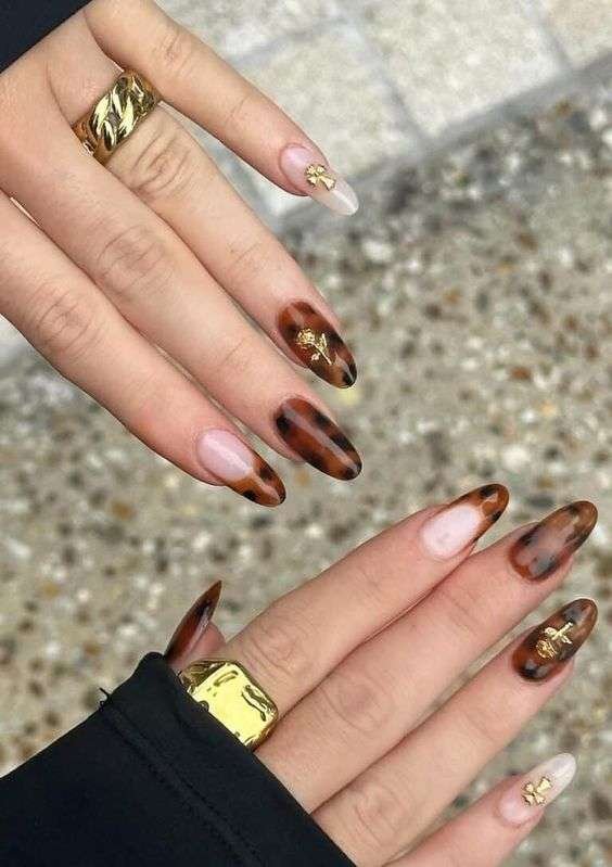 Elegant fall nail design with brown, gold, and beige tones featuring golden leaf patterns and marble effects.