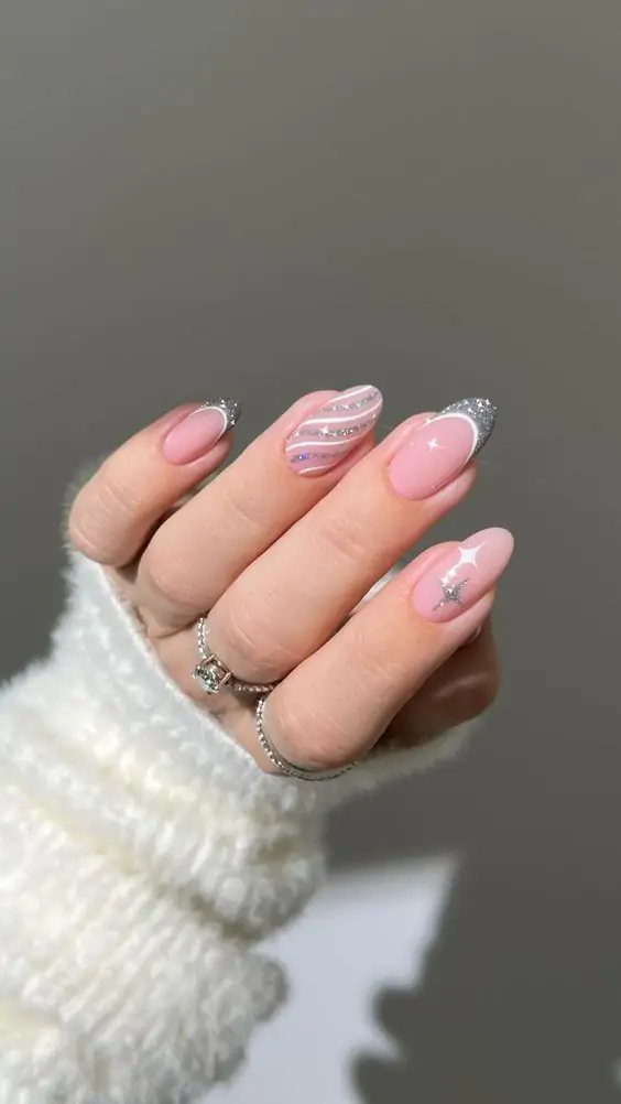 Winter Wonderland Nails: These nails feature a soft pink base with silver glitter tips, accented by elegant white and silver wavy lines, and adorned with tiny star embellishments. The design pairs perfectly with cozy winter vibes and delicate accessories, offering a sophisticated yet festive look for the season. The subtle hues and sparkling details make it a go-to choice for any winter event.