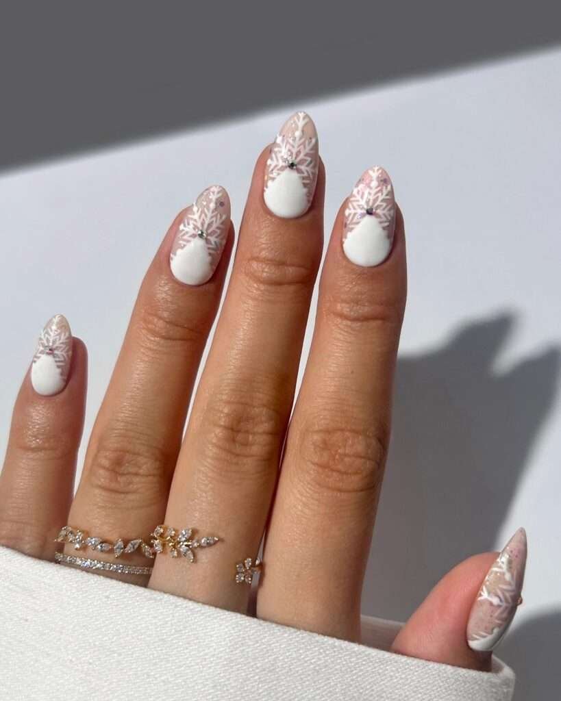 These almond-shaped nails feature a clean white base, beautifully decorated with detailed snowflake designs and tiny rhinestones. To finish off the look, add delicate gold rings with small diamonds for a touch of elegance.