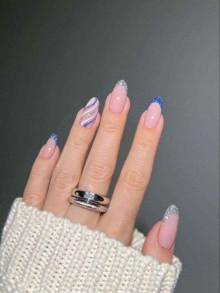 Some nails feature a soft, milky pink base, like the early morning sky, accented with either a dazzling silver glitter tip, reminiscent of frost, or a deeper blue glitter, like the approaching dusk. One nail showcases playful, swirling stripes of white, silver glitter, and blue glitter, like wisps of clouds catching the light. This design is delicate and dreamy, evoking the serene beauty of a winter day.