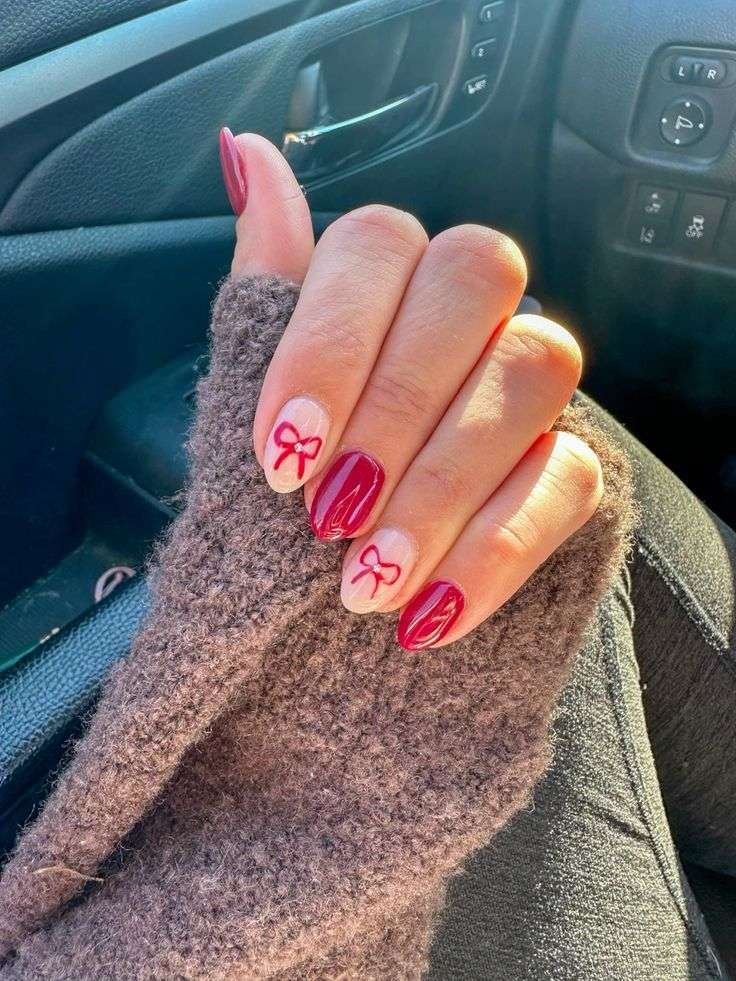 This charming manicure features a rich crimson red on most nails for a deep, festive color. A few accent nails showcase a soft, milky white base adorned with delicate, hand-painted crimson bows. The simple yet elegant design adds a touch of sweetness and holiday cheer, perfect for a subtle Christmas look.