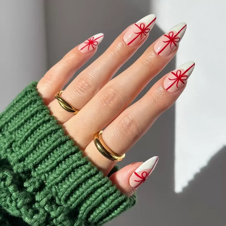 This charming manicure features a delicate, sheer base with crisp white tips, reminiscent of a blank canvas ready for holiday cheer. Each nail is adorned with a hand-painted red ribbon design, creating the illusion of perfectly wrapped gifts. The simple yet elegant design captures the spirit of giving and adds a touch of festive sweetness to any holiday look.