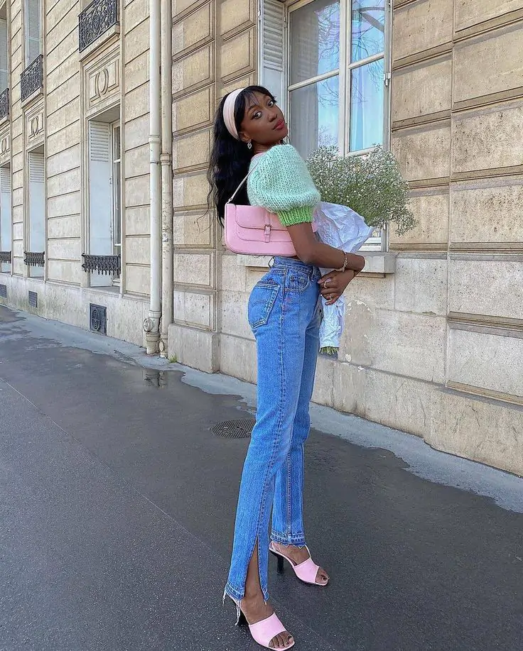 Step into spring with a light green short-sleeved sweater paired with high-waisted blue jeans featuring slits at the bottom. Add a pop of color with pink high-heeled sandals and a matching pink handbag. Complete the look with a bouquet of white flowers for a fresh, stylish touch.