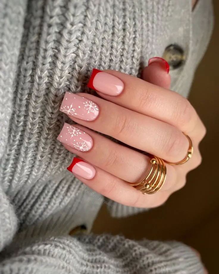 These festive nails feature a soft pink base with a bold red tip and delicate snowflake designs. The combination of classic colors and wintery motifs creates a sophisticated and elegant look, perfect for the holiday season.