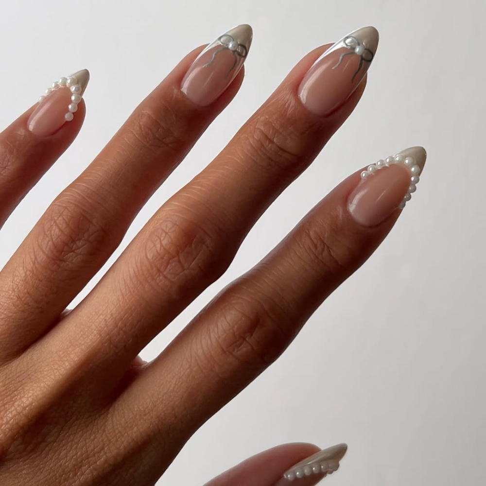 The nails have a sheer, natural base, giving them a clean and elegant look. The tips are adorned with either a thin line of shimmering silver, like a delicate trace of frost, or a row of tiny pearls, resembling frozen droplets. The pearls add a touch of texture and dimension, creating a subtle yet captivating effect. This design is understated and refined, capturing the quiet beauty and delicate details of a winter landscape. It's perfect for those who appreciate subtle elegance and understated glamour.