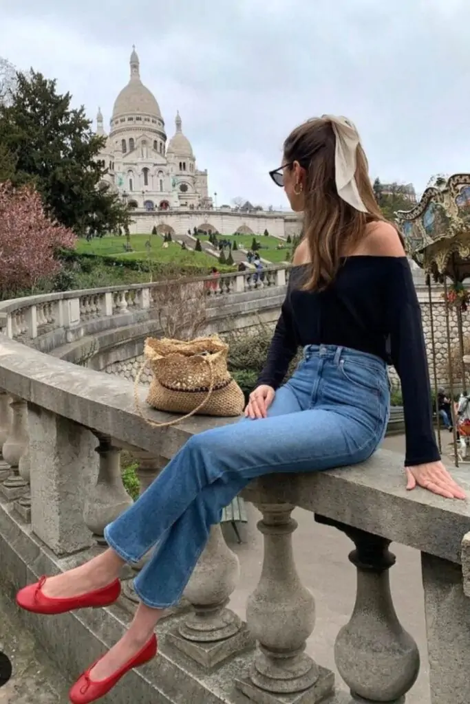 Imagine a sunny afternoon in Paris, relaxing by the Sacré-Cœur Basilica. You're wearing a stylish black off-the-shoulder top and high-waisted blue jeans that perfectly capture the spring vibe. Red ballet flats add a pop of color, and a woven straw bag adds a touch of boho-chic. Perfect for a day of sightseeing and café hopping.