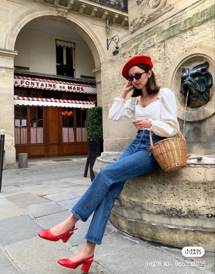 Imagine a stroll through Paris with this effortlessly chic ensemble. You're donning a red beret that adds a classic touch to your style. A white blouse with puffed sleeves and blue jeans create a perfect blend of elegance and casual comfort. The red high-heeled shoes and a wicker basket complete this charming look, ideal for exploring the city’s picturesque streets and fountains.
