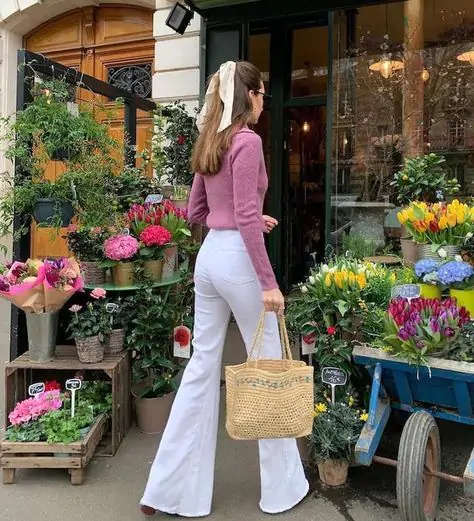 Embrace the spring vibe with this stylish look: a pink sweater paired with white flared pants. Complete the look with a woven basket, adding a touch of rustic charm. Perfect for a day out at the flower shop, exuding elegance and freshness.