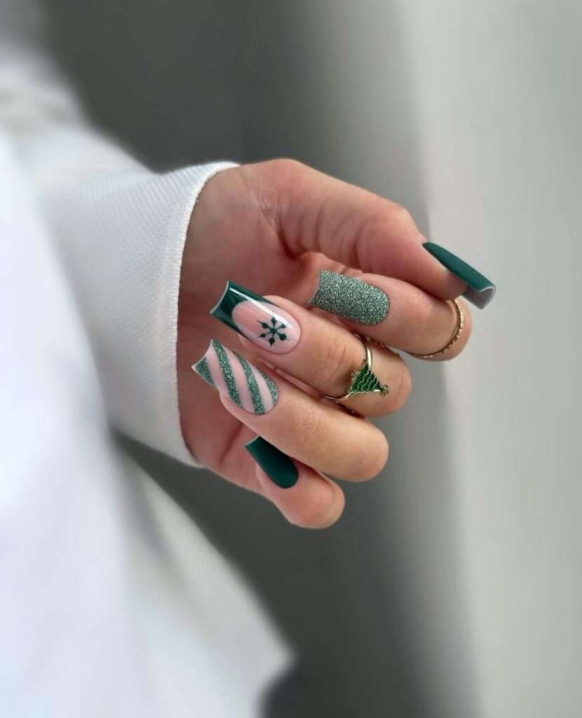 This manicure evokes a winter forest with varying shades of deep emerald green. Some nails feature solid green, while others have a delicate pink base adorned with a frosty green snowflake or shimmering stripes. The contrast between the rich green and the soft pink, combined with the glittery accents, creates a magical, wintry feel.