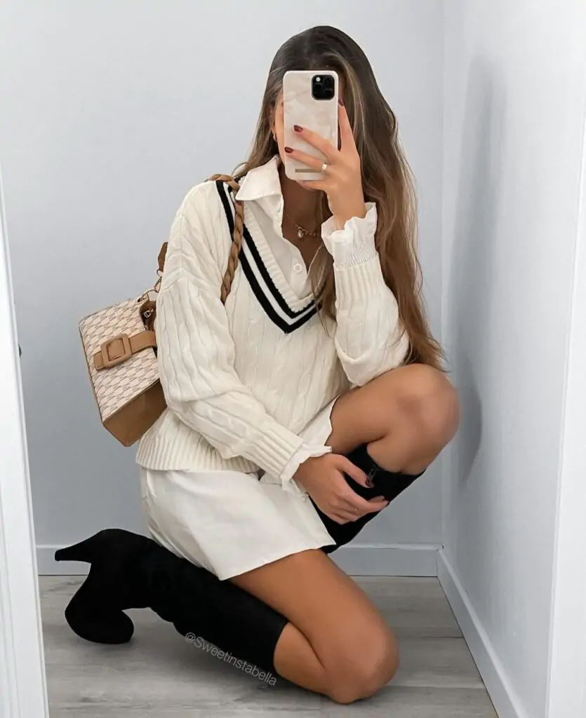 Perfect for a fresh and sophisticated spring look. A chic white sweater with black stripes on the collar layered over a crisp white shirt creates a refined yet relaxed vibe. Paired with a stylish white skirt, this outfit is elevated with black knee-high boots and a beige handbag featuring a checkered pattern and brown strap for a touch of elegance.