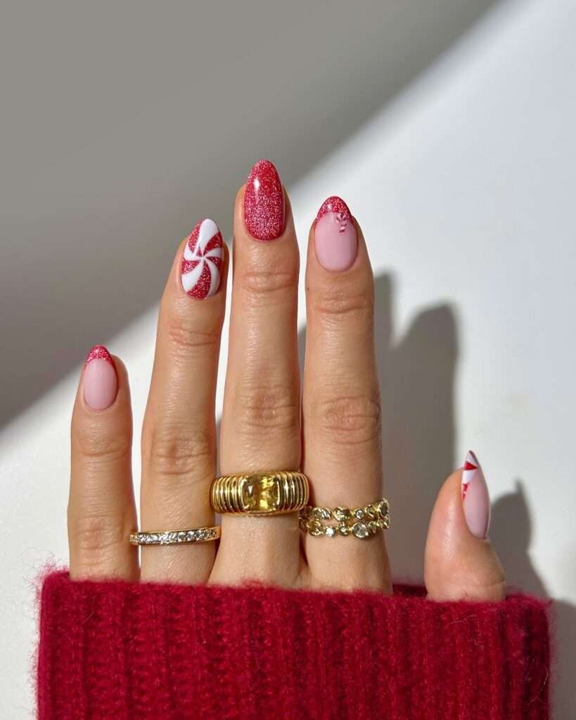 Festive manicure captures the sweetness of the holidays with a fun peppermint candy theme. One nail features a classic red and white peppermint swirl design, while others showcase a delicate pink base with a red glitter tip or subtle candy cane stripes. The combination of the swirling design, glitter accents, and candy cane stripes creates a playful and delightful Christmas look.