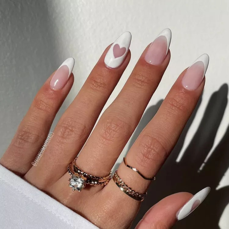 A classic French manicure gets a romantic twist with delicate white hearts painted on the tips of almond-shaped nails. The design is simple yet elegant, making it perfect for celebrating Valentine's Day.