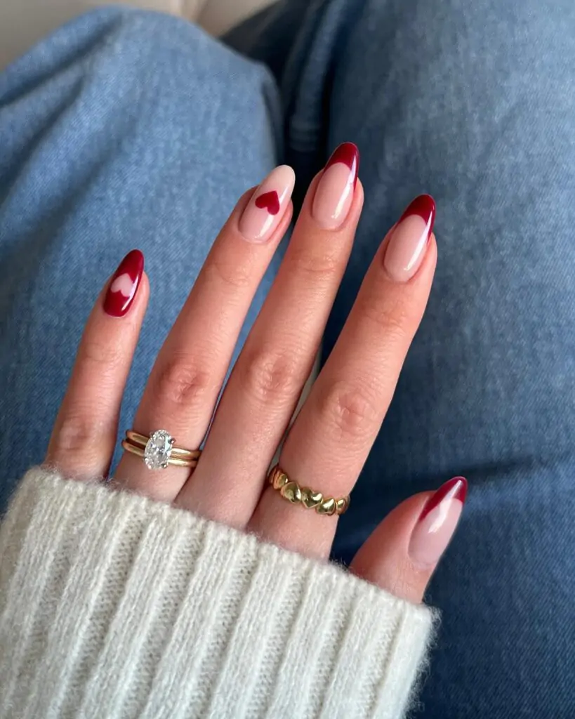 This is a modern take on the classic French manicure with a touch of Valentine's Day charm. The clean, crisp red tips are elegantly balanced by the subtle heart accents, creating a sophisticated and romantic look. The almond shape of the nails elongates the fingers, making this a flattering choice for any hand shape.