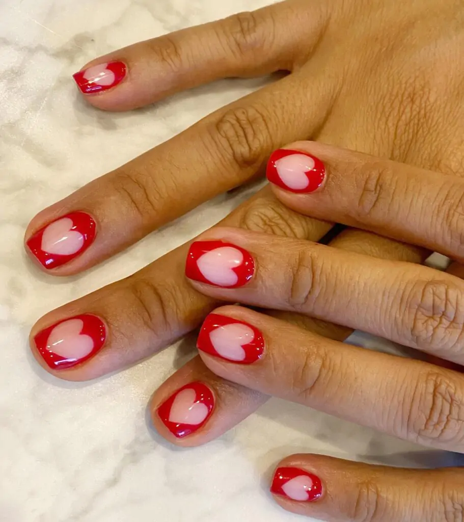 Fall head over heels for this playful Valentine's Day manicure! Each square nail is painted a bold red, but the real showstopper is the delicate heart shape peeking through, revealing a soft, romantic nude underneath. It's a design that's both sweet and sassy – perfect for spreading the love!