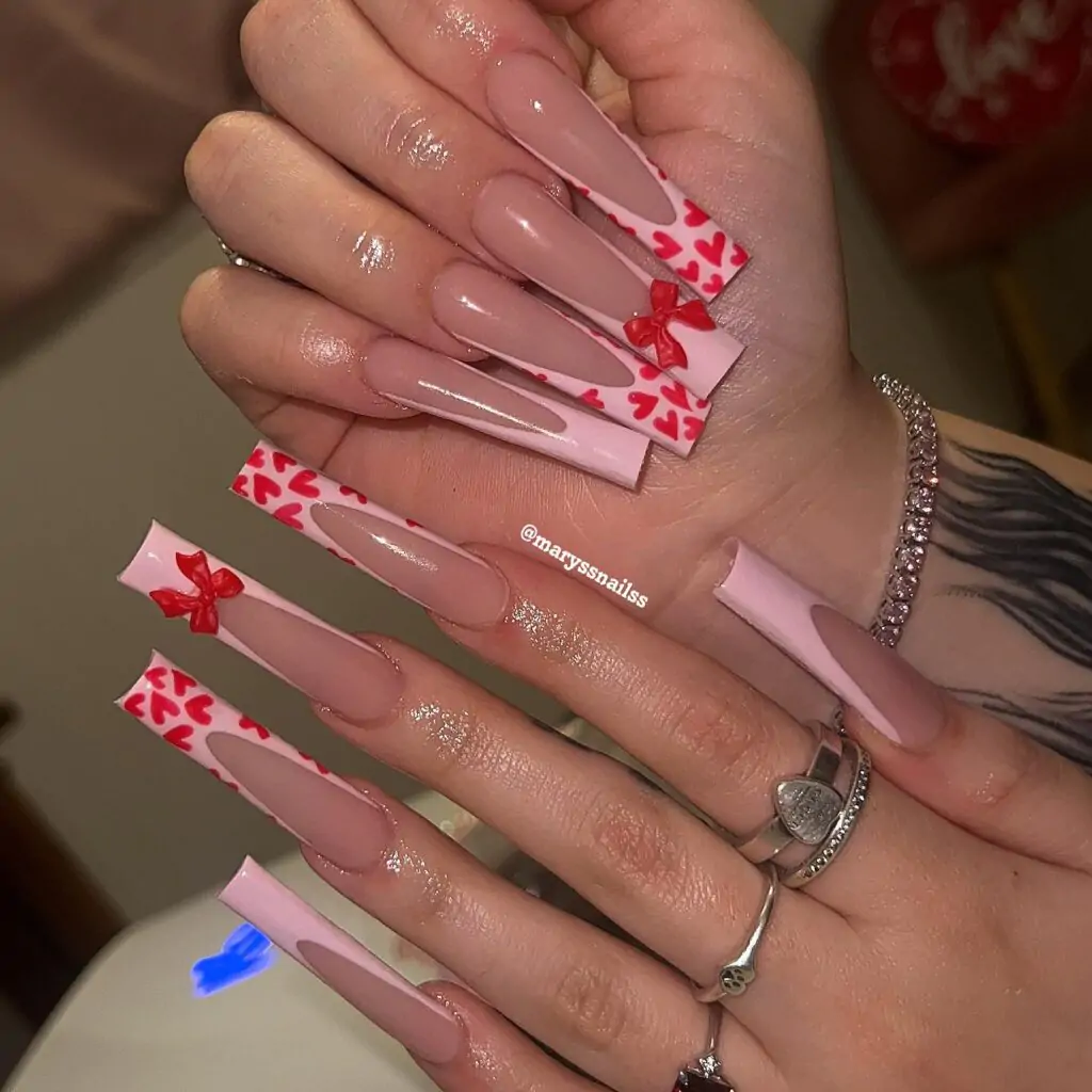 Get ready to steal the show with these extra-long, heart-shaped French tips! The playful pink and white design is elevated with adorable little bows and scattered red hearts, creating a look that's both sweet and sassy.