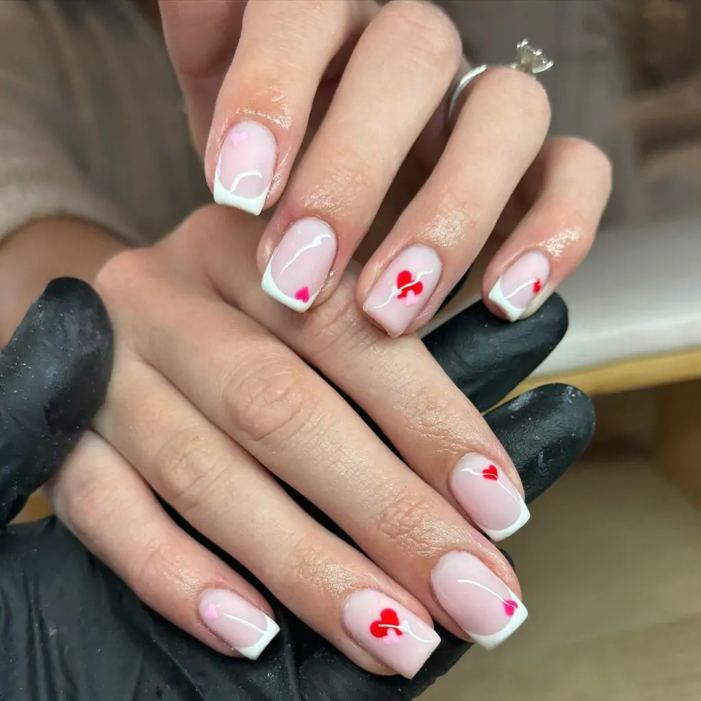 Imagine a light breeze carrying tiny hearts across your fingertips! This sweet and playful manicure features a classic French tip with a whimsical twist – little red hearts seem to float above the white line, adding a touch of whimsy and romance. It's like capturing the feeling of falling in love all over again.