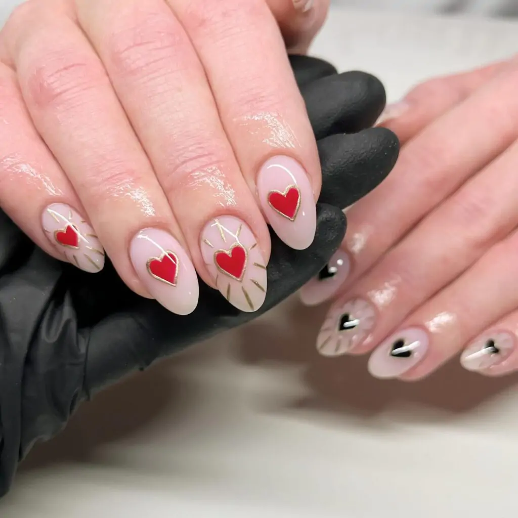 Elevate your Valentine's Day look with this sophisticated and romantic nail art! Each almond-shaped nail is adorned with a delicate red heart embellished with a shimmering gold outline. It's a design that's both elegant and playful, perfect for those who love a touch of luxury.