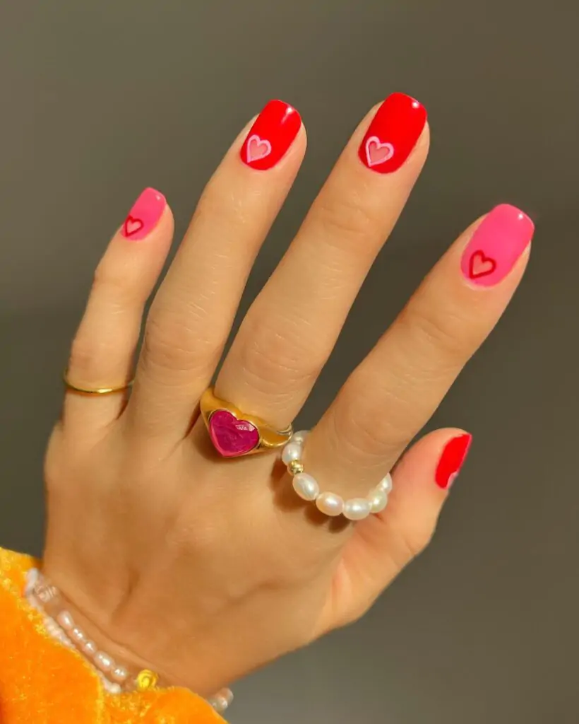 Spread the love with this adorable heart-filled manicure! Each short, square nail is painted in a vibrant shade of pink or red, and accented with tiny white hearts. It's a simple yet cheerful design that's perfect for Valentine's Day or any day you want to express your love.