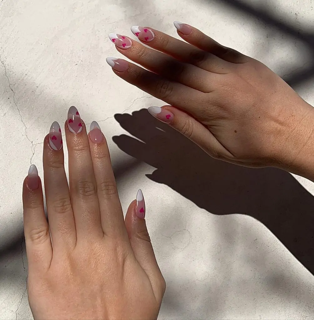 Say "Bonjour" to your new favorite French manicure! This classic look gets a playful update with tiny pink hearts scattered across the tips of each almond-shaped nail. It's a sweet and stylish way to show off your love for all things chic.