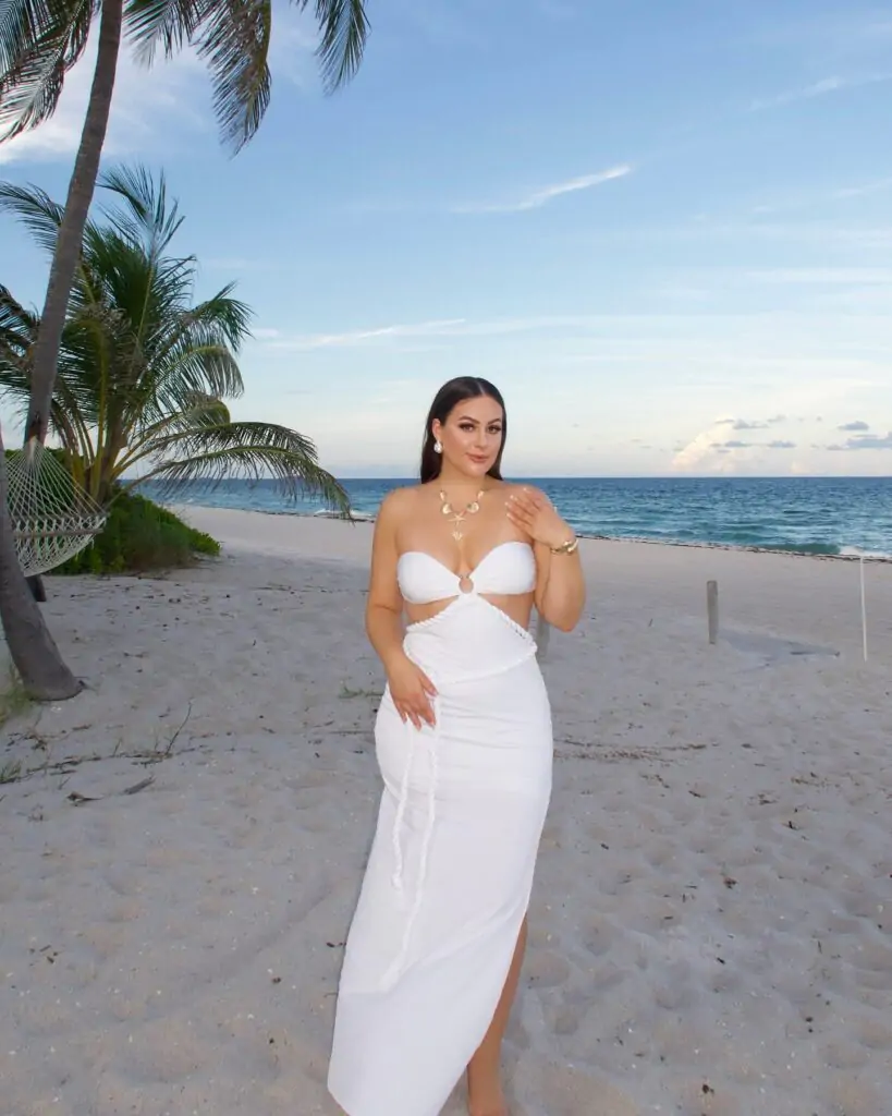 A chic white cut-out dress with a halter neckline and thigh-high slit for a sophisticated and stylish beach look.