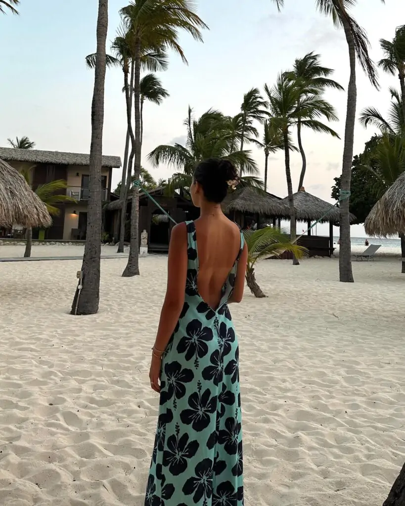chic, backless maxi dress adorned with bold floral prints, perfect for a tropical beach getaway, exuding effortless elegance and island vibes.