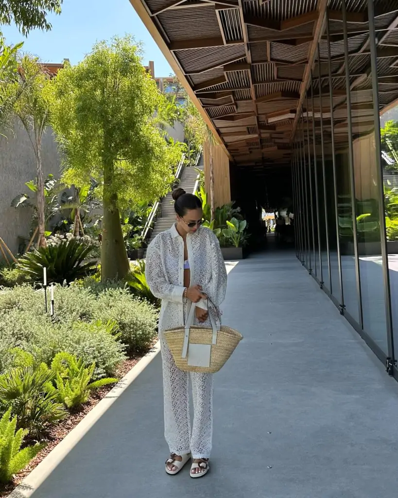 Elevate your beach style with a white lace cover-up set, woven straw tote, and chic white sandals for a sophisticated coastal vibe.