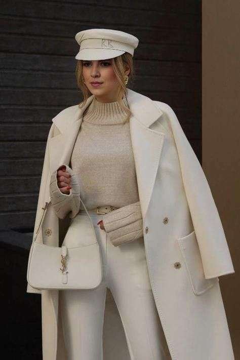 The Ultimate Tonal Statement: This look masterfully layers creamy neutrals, featuring a sharp, structured white coat over a soft, beige turtleneck and chic leather trousers. Headwear Hero: The unexpected addition of a crisp white baker boy cap and matching wrist-length knit gloves injects a unique, sophisticated nautical flair to the winter ensemble. Pure Luxury Finish: The clean lines are completed with a monochromatic white shoulder bag and simple gold earrings, creating a visually rich yet effortless high-fashion moment.