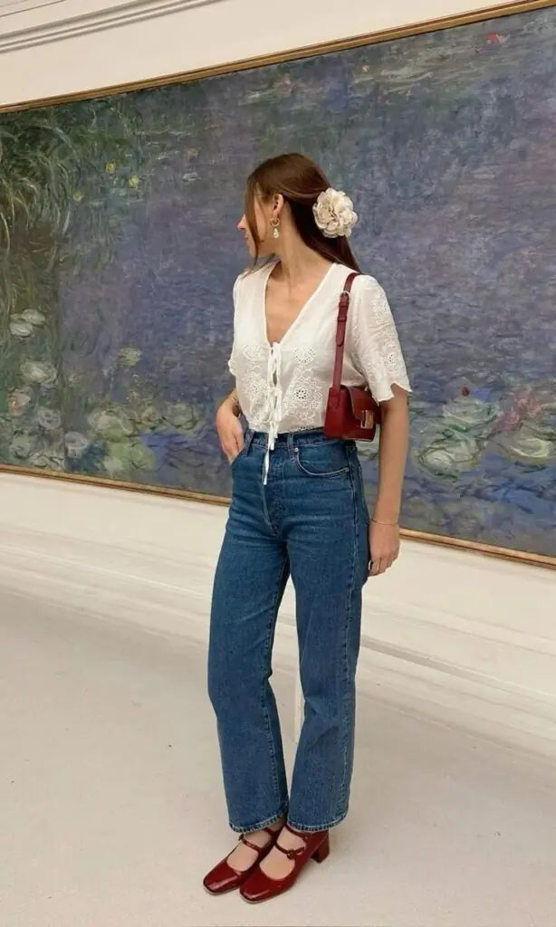 An Ecru Laure Blouse from Easy Clothes. It is a lightweight, fluid blouse featuring short sleeves, embroidered eyelet fabric, and delicate bow ties on the front. Similar styles include the Embroidered Blouse with Bows from Mango and the Island Dreamer Tie Front Eyelet Blouse from Pink Lily. Levi’s Ribcage Straight Ankle Jeans in a medium blue wash. These are iconic super high-rise jeans designed to sit at the narrowest part of the waist with a classic straight leg that hits at the ankle. Other verified matches for this specific style include the AGOLDE 90's Pinch Waist Jean and Jesse Kamm The 225 in Cowboy Blue.