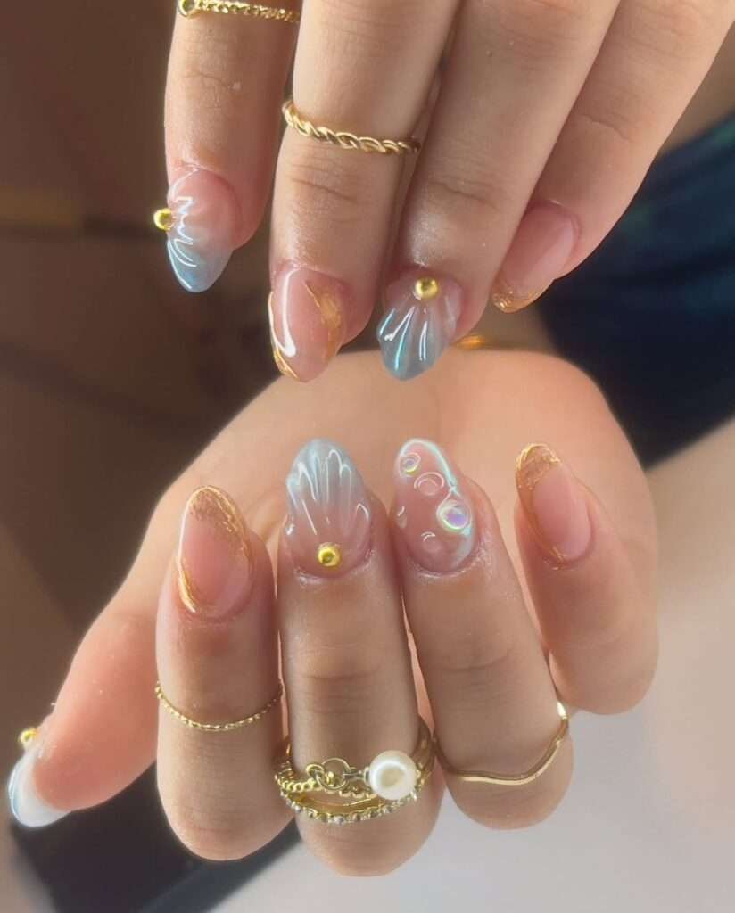 This vibrant nail art style is most commonly referred to as 3D Tropical Shell and Floral nails. The specific design featured in your image is often titled "Summer Wonder" by some nail artists and retailers. 3D Seashells: Textured, raised ridges that mimic the look of real shells, often accented with pearls. Tropical Florals: Hand-painted or 3D flowers, typically hibiscus or other island-inspired blooms in bright pinks, oranges, and yellows. Aura & Gradients: Soft, blended color backgrounds that create a "sunset" or "tropical" glow. Oceanic Accents: Small details like starfish, gold studs, and water droplets (using clear builder gel).