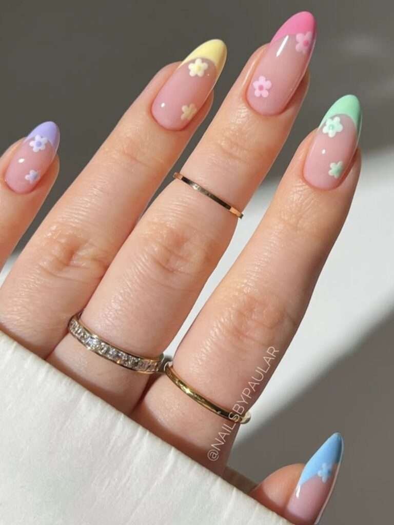 This vibrant and playful look is most commonly referred to as Pastel Rainbow French Tip nails with Floral Accents. n the 2026 nail scene, this specific aesthetic is also called "Skittle French" or "Cottagecore French" because it mixes different colors on each finger with dainty, nature-inspired details.