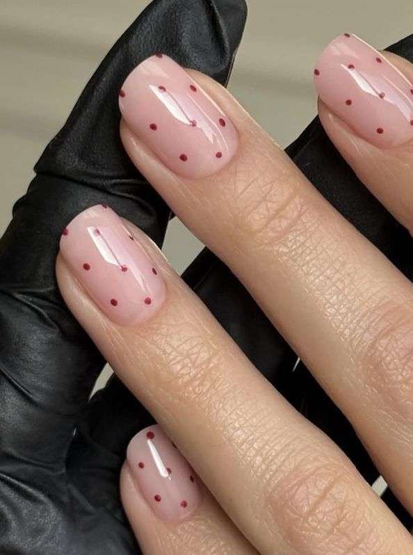 This chic, minimalist look is most commonly referred to as Cherry Polka Dot nails or Minimalist Red-on-Pink dots. In the 2026 nail scene, this specific aesthetic is also a staple of the "Clean Girl" or "Coquette-lite" trends, which emphasize simple, polished patterns on a healthy-looking natural base.