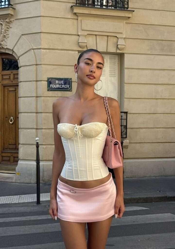 A hot pink pleated mini skirt with a delicate white or blush lace bustier top is a paradox that works perfectly in 2026. They're styling this with pointed-toe kitten heels and a tiny satin evening bag.