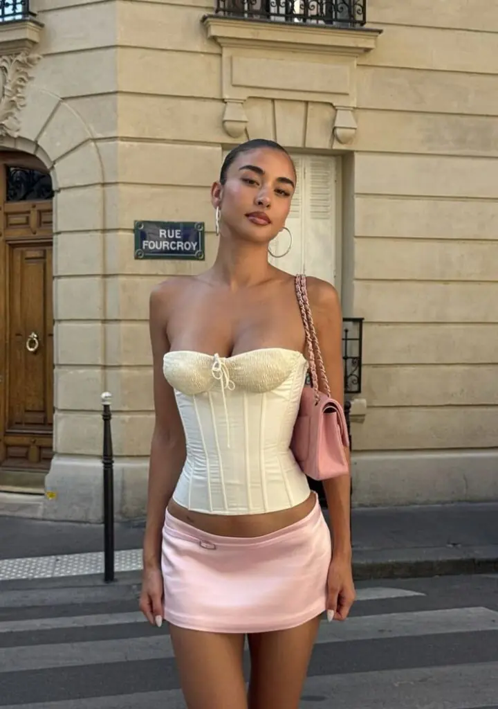 A hot pink pleated mini skirt with a delicate white or blush lace bustier top is a paradox that works perfectly in 2026. They're styling this with pointed-toe kitten heels and a tiny satin evening bag.