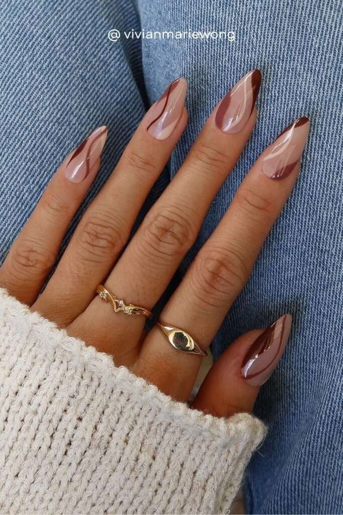 A chrome-glazed base with organic brown swirl shapes — part of the glazed donut meets abstract art nail moment of fall 2026.